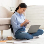 Espaldar corrector de postura para silla, joven escribiendo en cuaderno y laptop en el suelo.