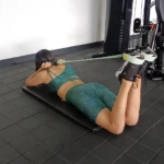Mujer realiza ejercicio de piernas con banda elástica en gym.