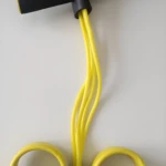 Banda elástica de resistencia amarilla y negra con manijas y pedales para ejercicio en casa.