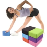 Mujer estirando con bloques de yoga de espuma de colores: azul, negro, verde, naranja, morado, rosa.