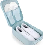 Bolso de viaje azul con zapatillas blancas y chanclas en compartimentos de malla.