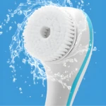 Cepillo de baño eléctrico blanco con cerdas suaves recibiendo un chorro de agua refrescante.