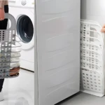 Cesta plegable multiusos gris con ropa y lavadora.
