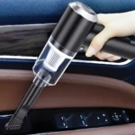 Aspiradora portátil negra de mano limpiando panel de puerta de automóvil con accesorios.