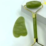 Combo Rodillo Jade y Gua Sha verde para cuidado facial, con detalles dorados y fondo blanco.