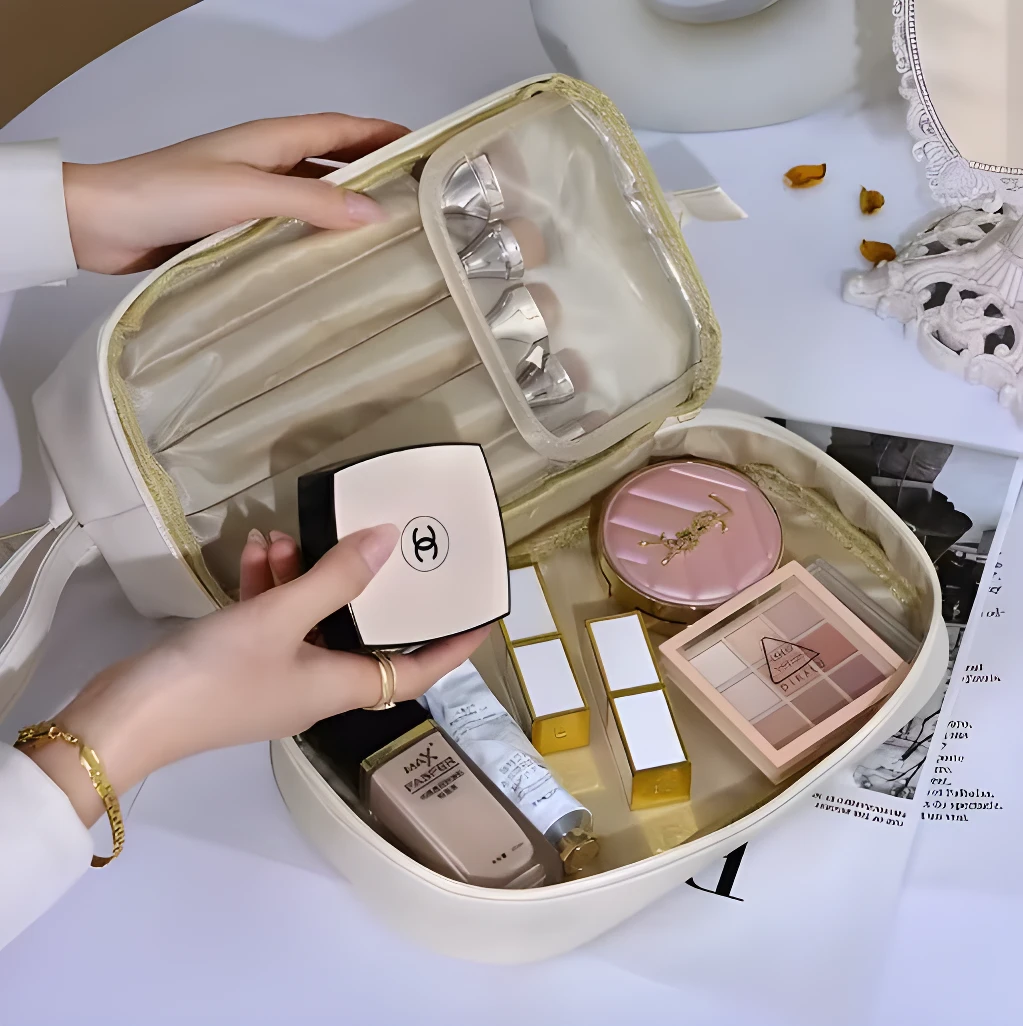 Cosmetiquera de doble compartimento con maquillaje de lujo Chanel, YSL y paleta de sombras.