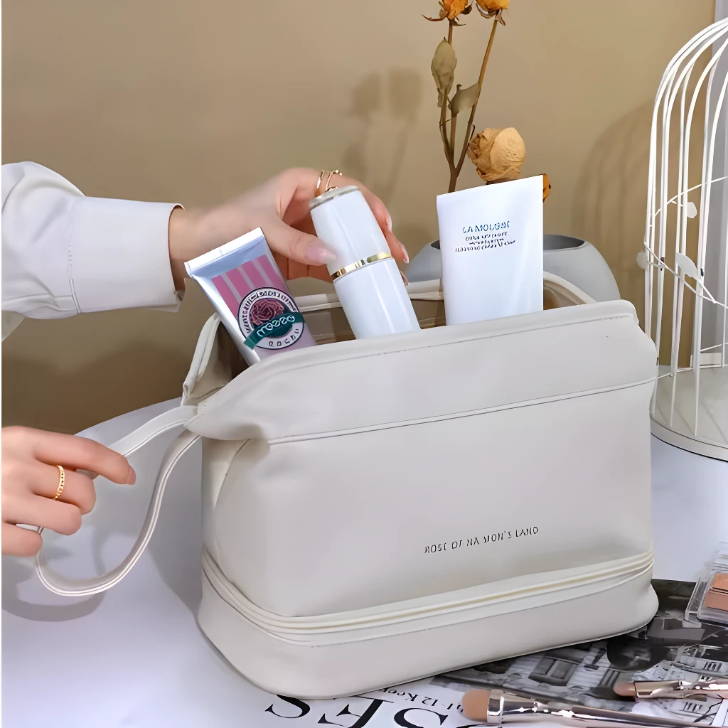 Cosmetiquera doble compartimento beige con productos de belleza, bolsa de mano práctica.