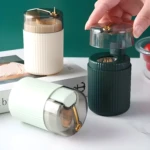 Dispensador automático de palillos verde, blanco y beige con tapa transparente y palillos visibles.