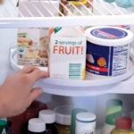 Estante giratorio para organizar la nevera con envase de "2 servings of FRUIT!" y mantequilla.