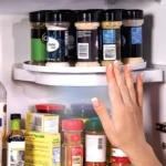 Estante organizador giratorio para especias en refrigerador con mano de mujer tocando.