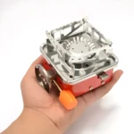 Estufa a gas butano portátil compacta en mano, ideal para camping y exteriores.