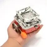 Estufa a gas butano portátil compacta en mano, ideal para camping y exteriores.
