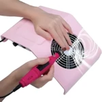 Extractor de polvo para uñas rosa con broca eléctrica y manos manicuradas.