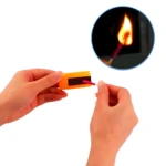Fósforo de camping F01 impermeables en acción, prendiendo con caja naranja.
