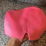 Gorro para migraña relajante rosa brillante en mano, ideal para alivio del dolor.