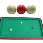 Tres bolas de billar de carambola de lujo, dos blancas y una roja, sobre mesa verde.