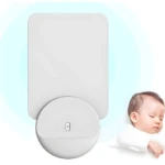 Lámpara para matar mosquitos blanca en forma de disco y panel, junto a un bebé durmiendo.