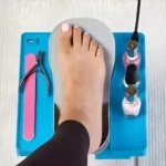 Mesa para pedicure con pie sobre soporte y esmaltes de uñas.