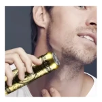 Mini afeitadora eléctrica profesional dorada en acción, afeitando el cuello de un hombre.