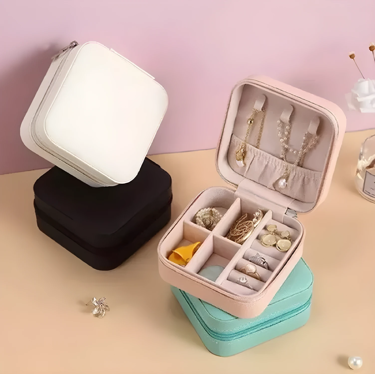 Mini organizador viajero para joyas abierto con collares y anillos en tonos pastel y blanco.