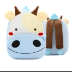 Mochila infantil de vaca azul con cara sonriente, orejas, cuernos y correas marrones.