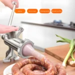 Molino de carne manual plateado haciendo salchichas en tripa natural con cebollín.