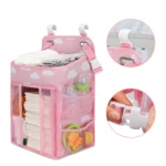 Organizador de bebé colgante rosa con compartimentos, ganchos y correas ajustables.