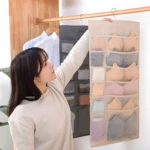 Colgador de closet con organizador de ropa interior, sostenes y calcetines beige en compartimentos.