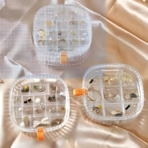 Organizador de joyero transparente con diferentes compartimentos y divisiones para anillos, aretas, collares y pulseras.