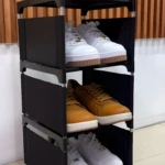 Organizador de zapatos 3 niveles en tela negra con tenis blancos y café.
