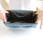 Organizador expandible azul para bolsos y maletas, con manos abriendo cremallera.