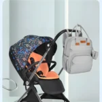 Pañalera gris con monedero cuelga del cochecito de bebé con capota estampada.