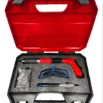 Pistola neumática para clavos de acero, con accesorios en su estuche rojo y negro.