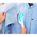 Plancha portátil de vapor Tobi alisando una camisa de rayas azules colgada, eliminando arrugas.