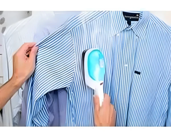 Plancha portátil de vapor Tobi alisando una camisa de rayas azules colgada, eliminando arrugas.