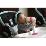 Bebé con porta teteros en silla alta para comer.