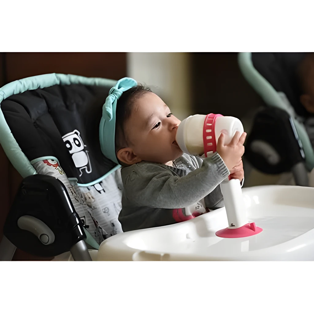 Bebé con porta teteros en silla alta para comer.