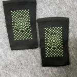 Rodillera elástica negra con puntos verdes para soporte deportivo y alivio de dolor.