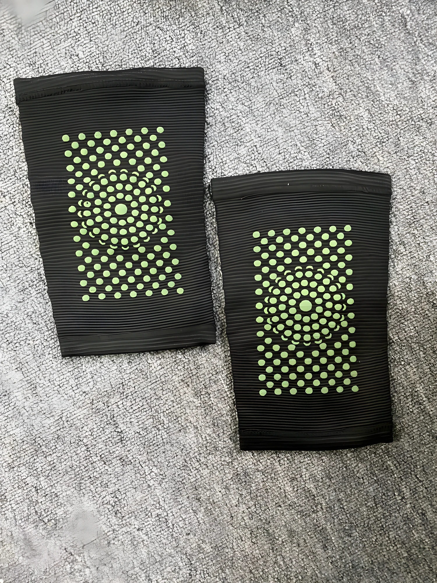 Rodillera elástica negra con puntos verdes para soporte deportivo y alivio de dolor.