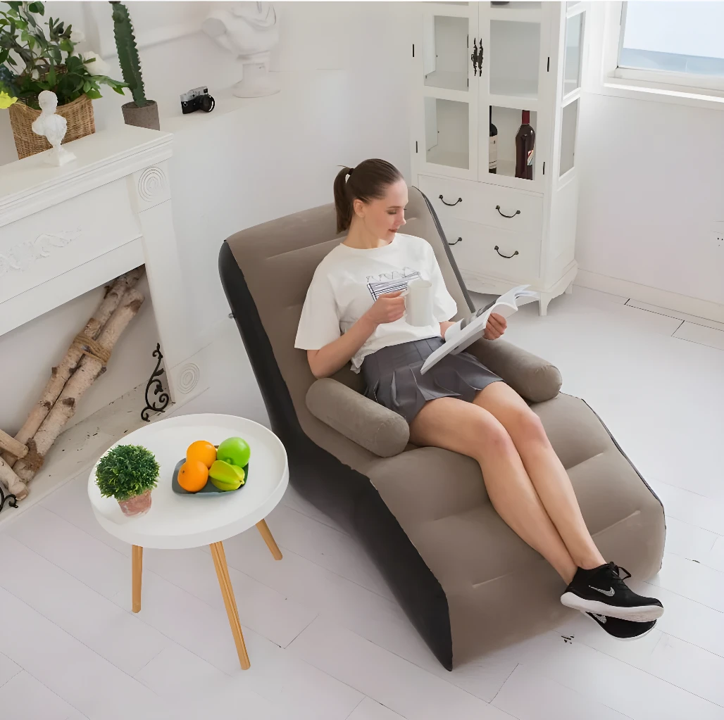 Sofá inflable reposa pies con mujer leyendo, mesa con frutas y planta decorativa.