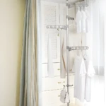 Tendedero vertical retráctil de piso para secar ropa blanca colgada en sus niveles.