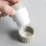 Triturador pulverizador de pastillas con tapa y compartimento para polvo blanco molido.