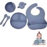 Vajilla de silicona para bebé con plato, tazón, cubiertos, babero y taza en tono gris.