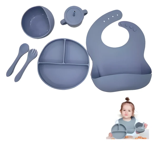 Vajilla de silicona para bebé con plato, tazón, cubiertos, babero y taza en tono gris.