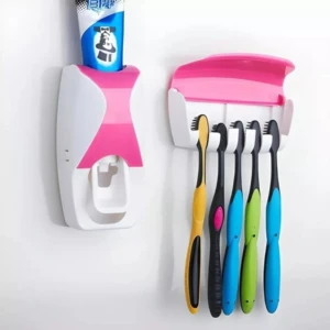 Dispensador automático de pasta dental blanco y rosa junto a soporte para 4 cepillos de dientes de colores.