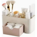 Organizador de maquillaje y cosméticos blanco con cajón rosa y compartimentos para brochas y productos.