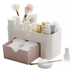 Organizador de maquillaje blanco con cajón rosa y compartimentos para cosméticos y brochas.