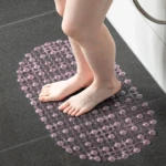 Tapete de baño de succión transparente con burbujas, se muestra en uso con pies descalzos sobre azulejo.