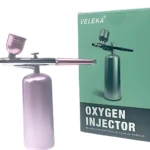 Aerógrafo Inalámbrico Portátil VELEKA color rosa metálico con cilindro y accesorio para inyección de oxígeno.