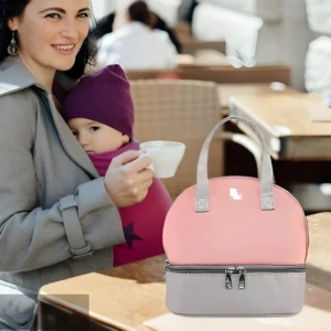 Bolso nevera para leche materna rosa y gris de doble compartimento, usado por madre con bebé.